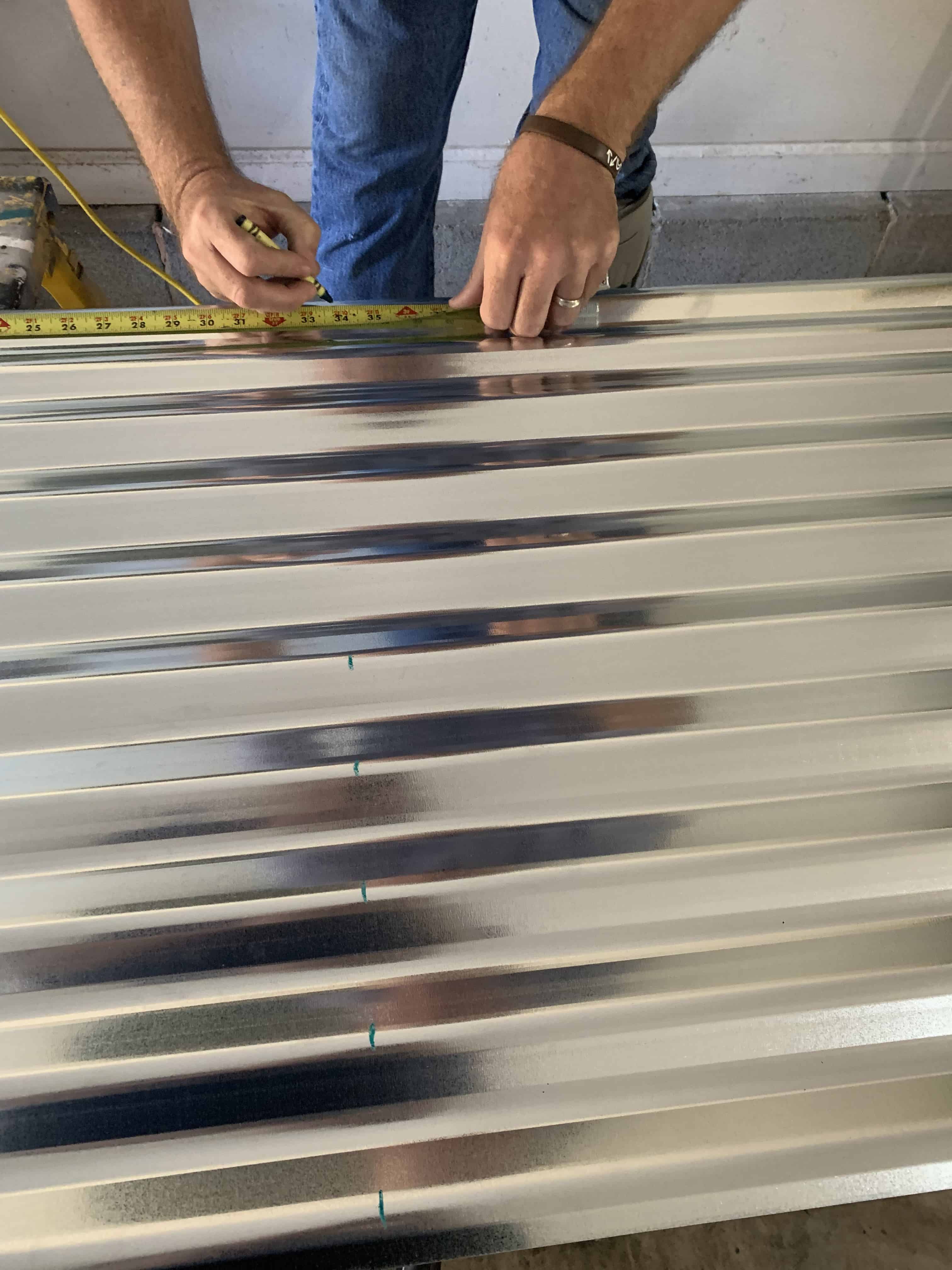 man measuring and marking tin with crayon